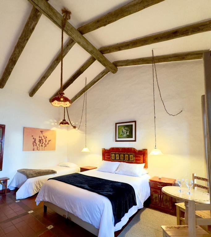 A twin room at El Pueblito, exposed roof beams and hanging lamps over a carved headboard