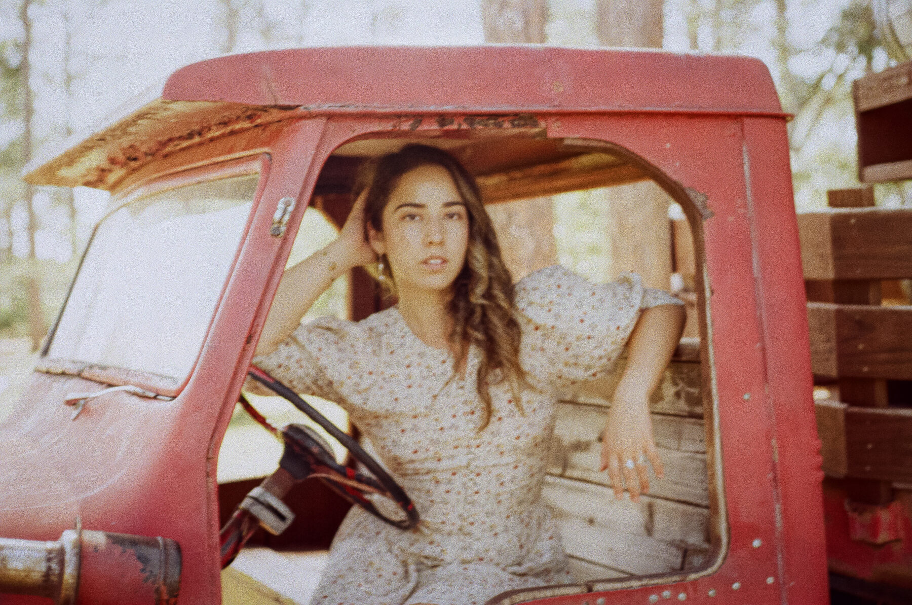 Dani Hurtado sitting in the cab of an old red pickup truck, arm resting on the window