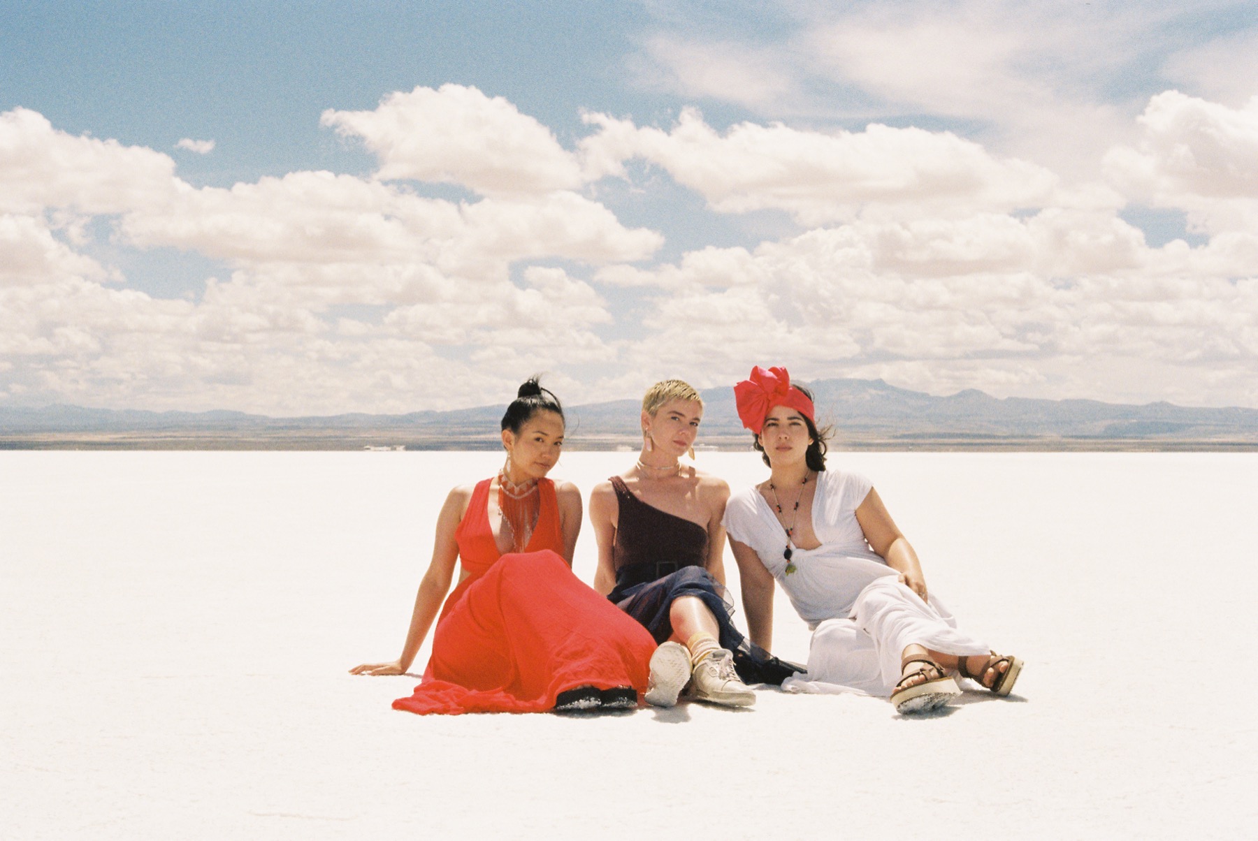 Three guests sitting together on the salt flats under a wide cloudy sky